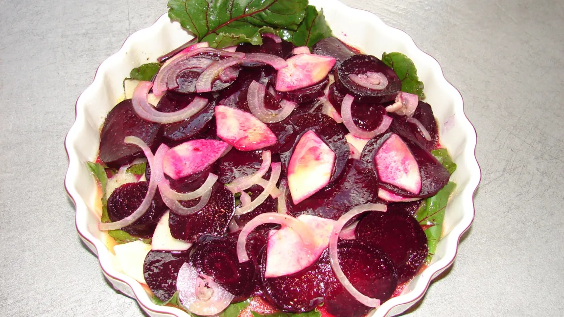 Rote Bete-Scheiben und Blätter mit Zwiebeln und Apfelstücken. Foto: Christa Nöhren/pixelio